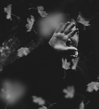 一幅描绘了被手和漂浮的树叶部分遮蔽的人的神秘黑白肖像