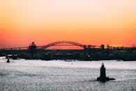 一座城市桥梁上，灯塔旁，日落景色令人惊叹，捕捉了海滨的宁静