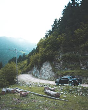 蜿蜒的山路上停着一辆汽车，周围环绕着郁郁葱葱的绿化和山丘