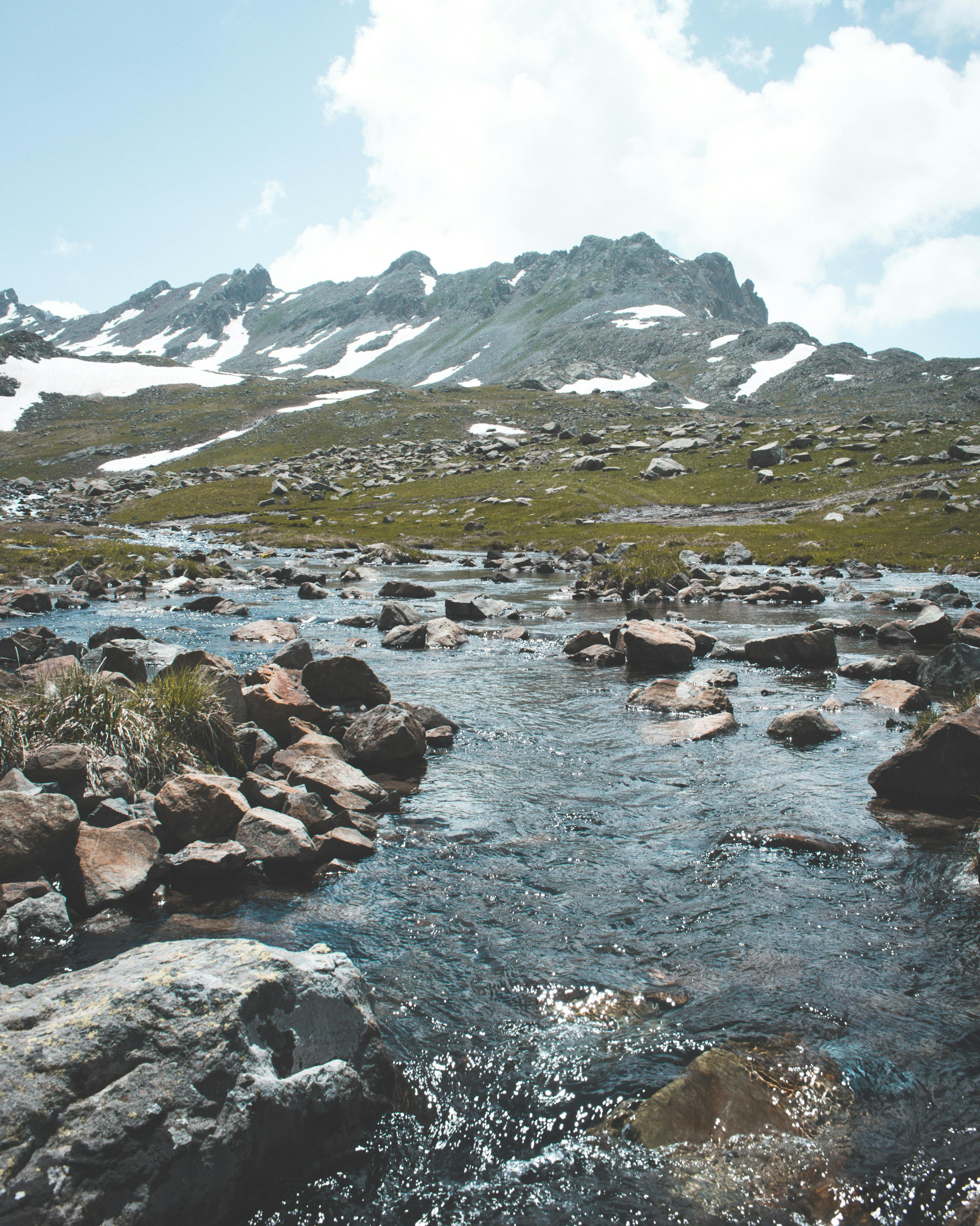 Prescription Goggle Inserts - Serenity of a bubbling stream flowing through rocky terrain with snow-capped mountains in the background.