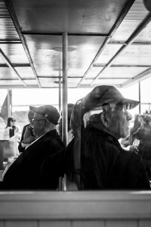Free Candid black and white image of senior men sitting on a ferry, showcasing urban travel atmosphere. Stock Photo
