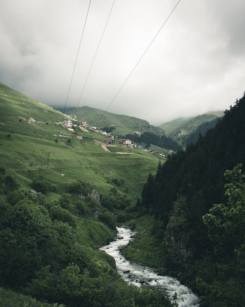 Houses in Green Field Viewing Mountain Under White Skies