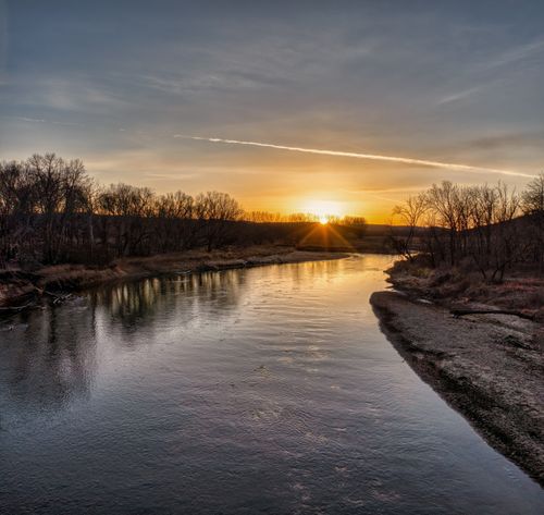 Free Beautiful sunset over a tranquil river with tree reflections in Minnesota's countryside. Stock Photo