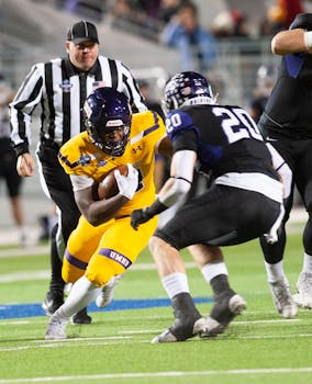 Dynamic college football game with athletes in action on the field, showcasing strategy and teamwork.