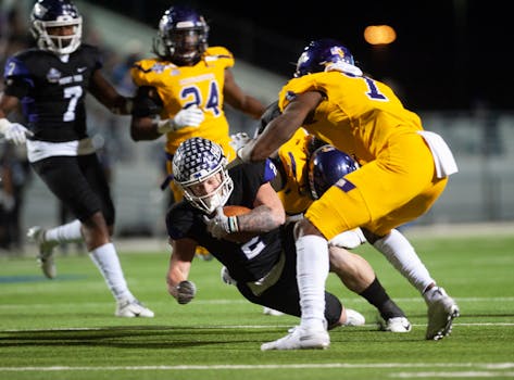 Dynamic football players in action during a night game, showcasing teamwork and athletic skills.