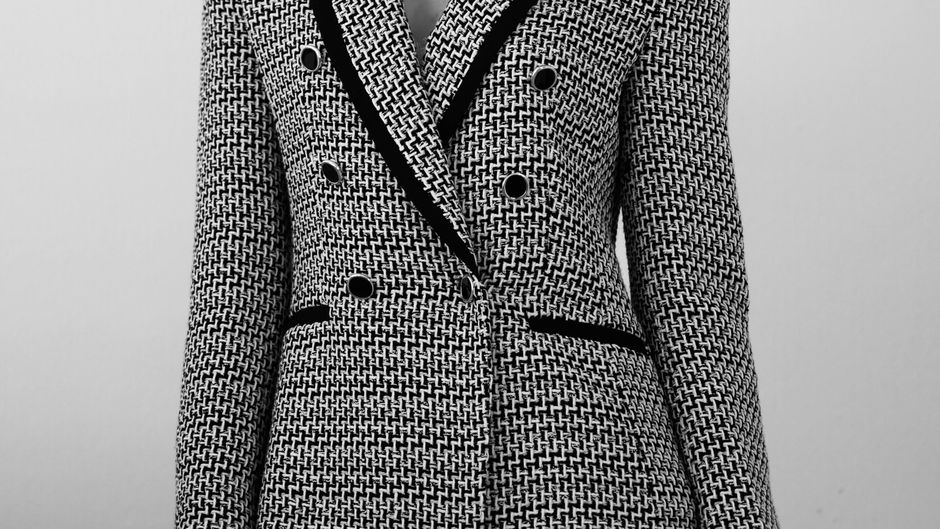 A cropped black and white tweed-style bouclé blazer with contrasting velvet lapels, showing a nubby statement jacket for texture mixing