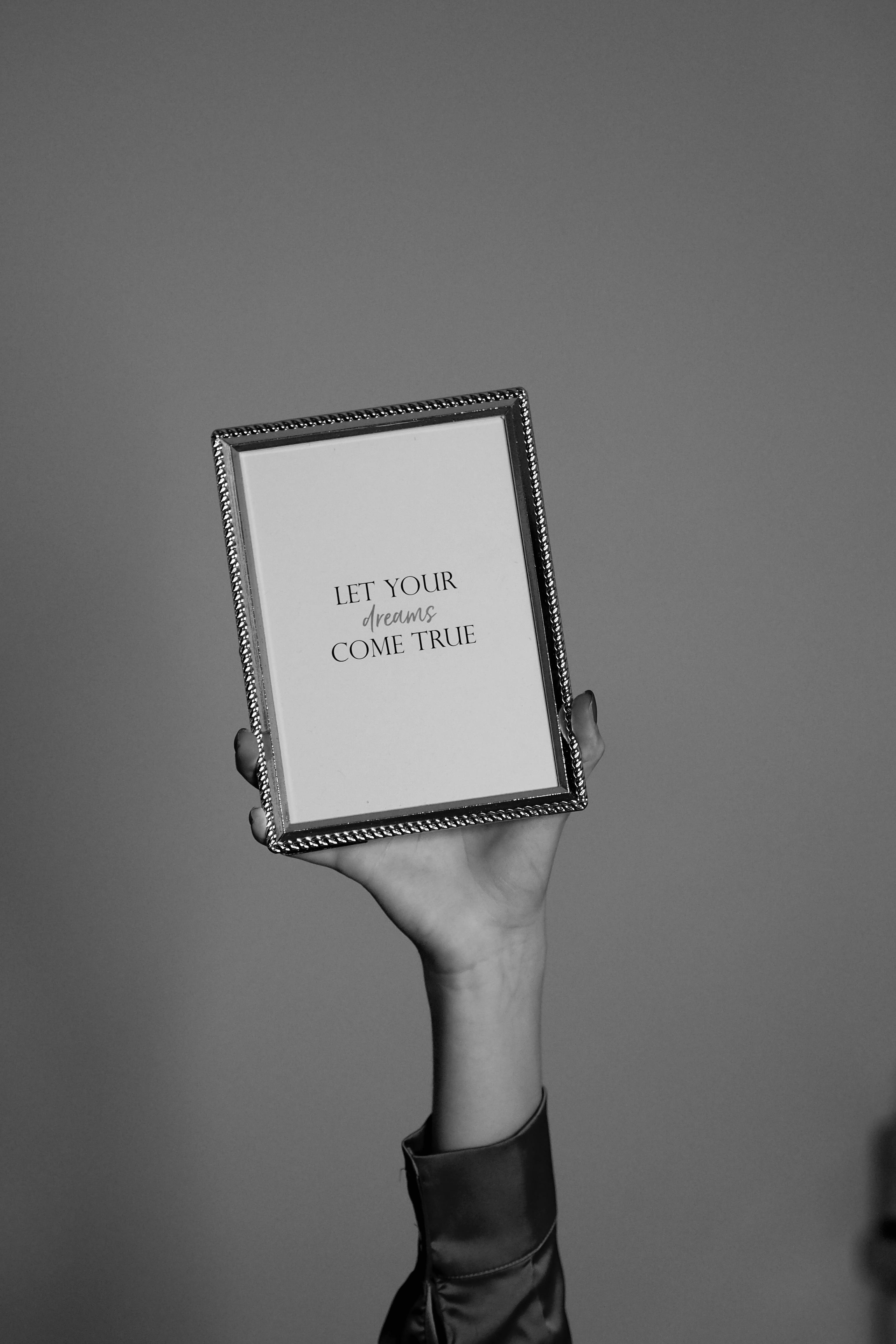 Hand holding a framed motivational quote in black and white.