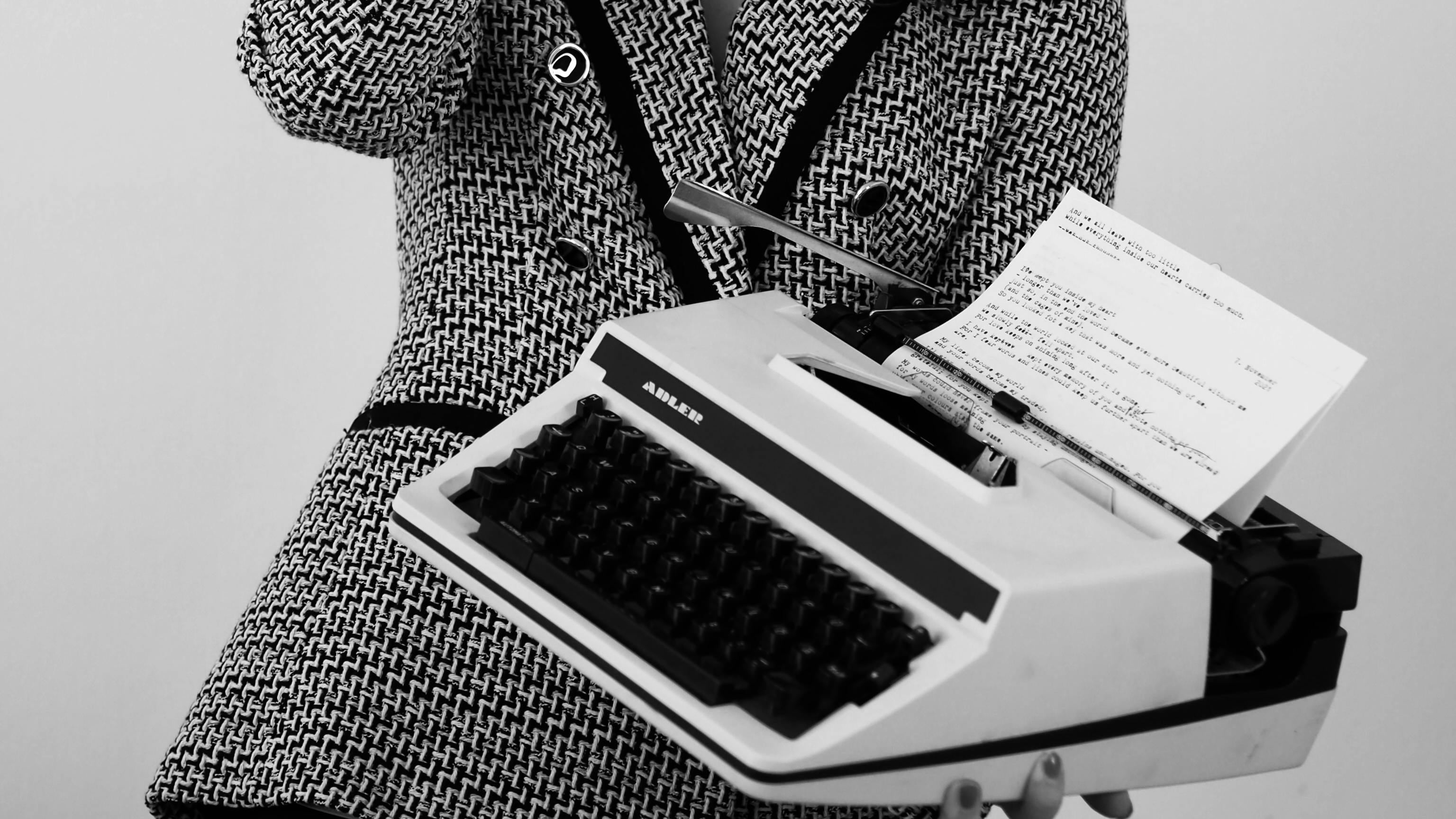 A woman in a suit holding a typewriter