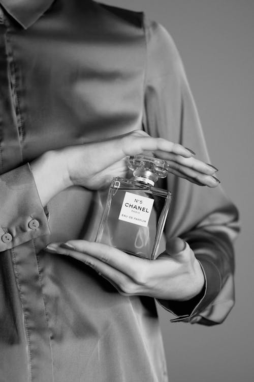 Woman in Satin Blouse Holding Bottle of Expensive Perfume