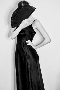 Chic black and white photo of a woman elegantly posing with a fan.