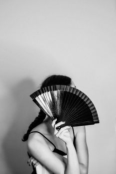Elegant black and white portrait of a woman posing with a hand fan.