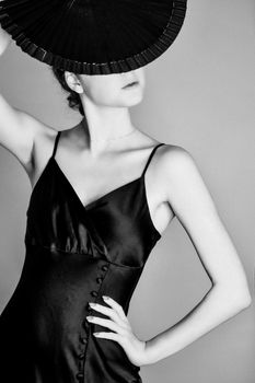 Black and white studio shot of a woman in a satin dress holding a fan, Paris.