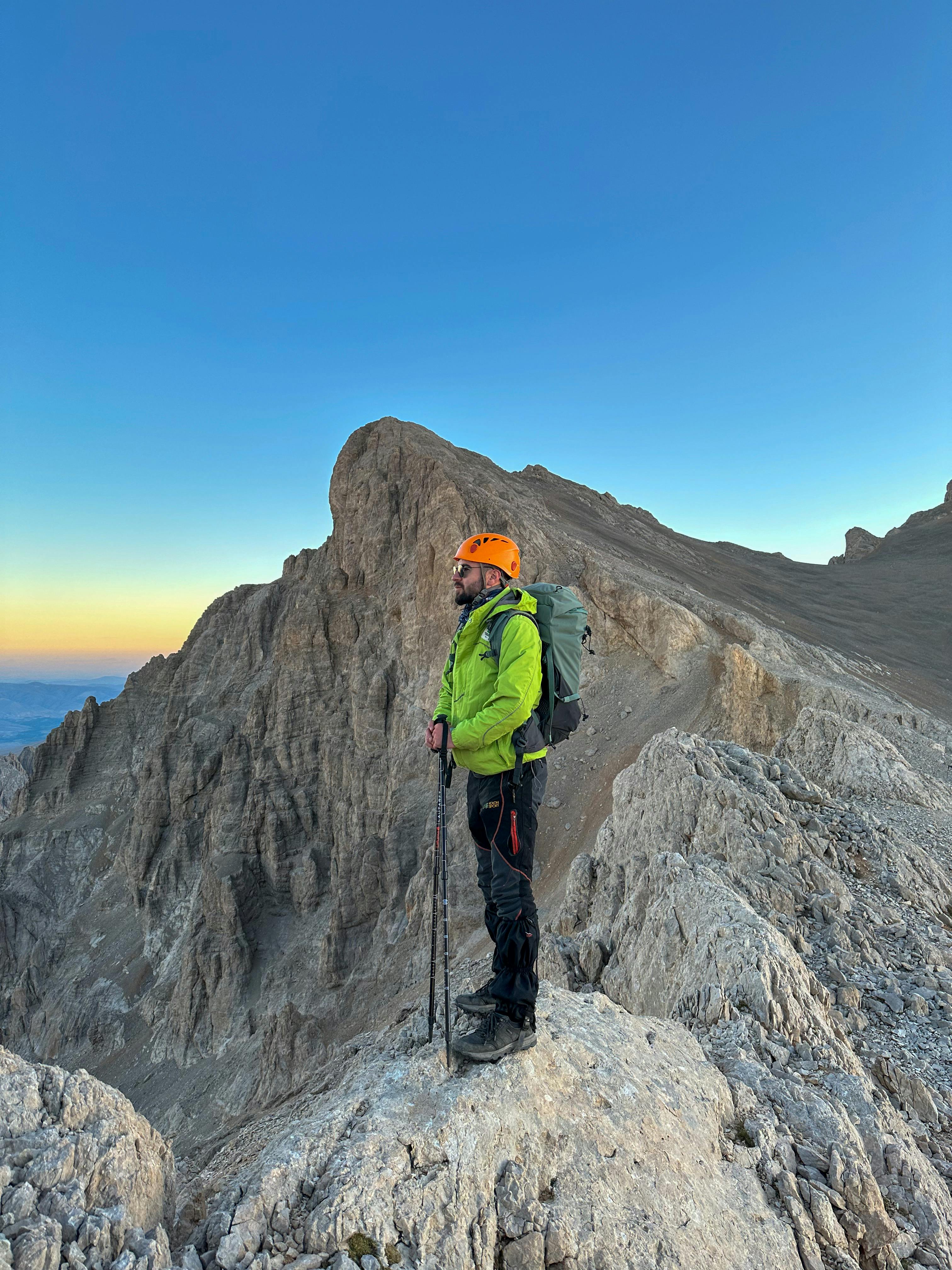 Hiker standing on Demirkazık Peak in Türkiye at sunrise, enjoying the mountain view.