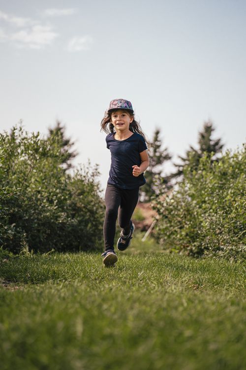 Free A young girl joyfully runs through a rural field on a sunny summer day. Stock Photo