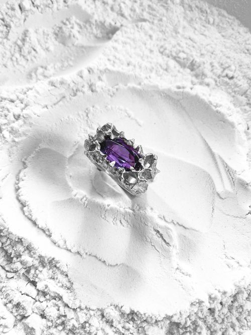 Free Stunning silver ring featuring a purple jewel against a textured white background showcasing elegance and contrast. Stock Photo