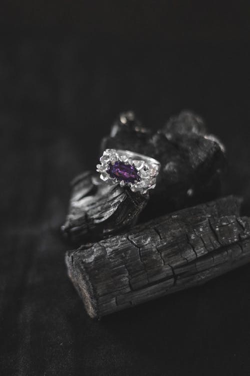 A purple stone ring sitting on top of a piece of wood