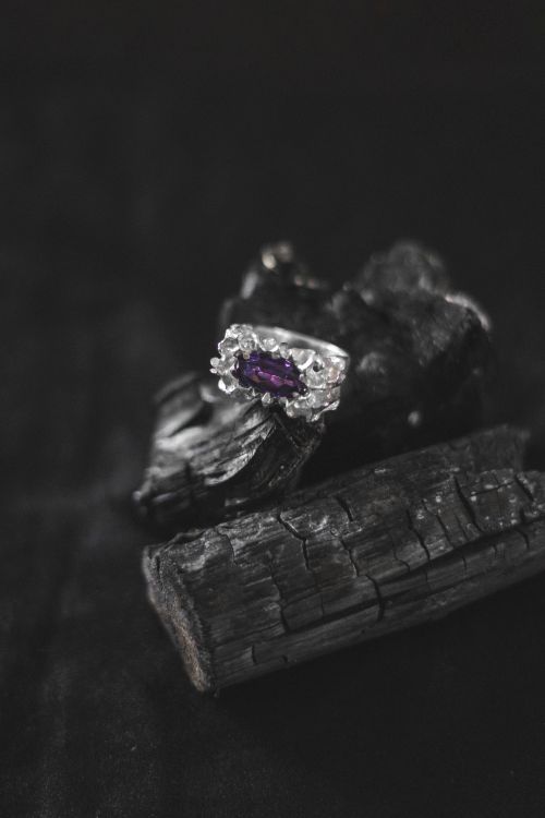 Free Close-up of a stylish silver ring featuring a striking purple gemstone set against a dark, rustic background. Stock Photo