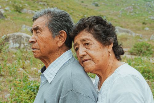 Free An elderly couple embraces lovingly in a serene outdoor setting, surrounded by nature. Stock Photo