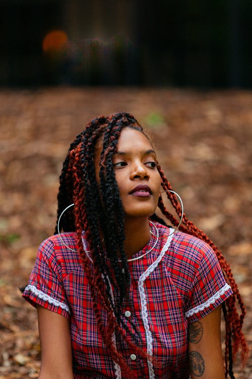 A woman with red hair and dreadlocks sitting in the woods