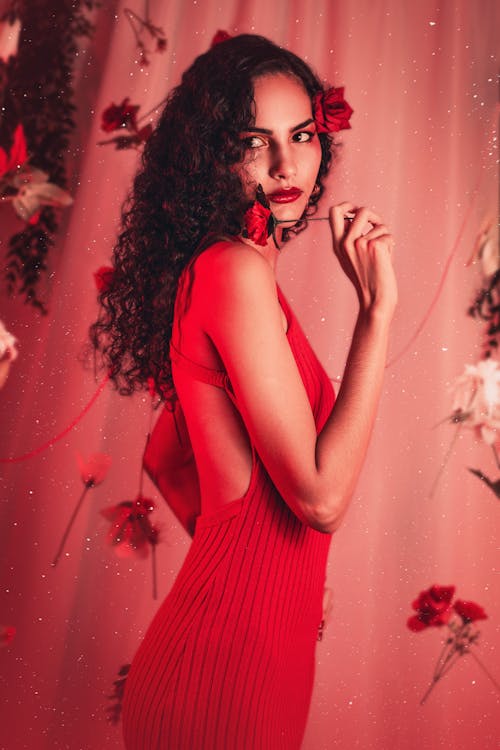 A woman in a red dress posing in front of flowers