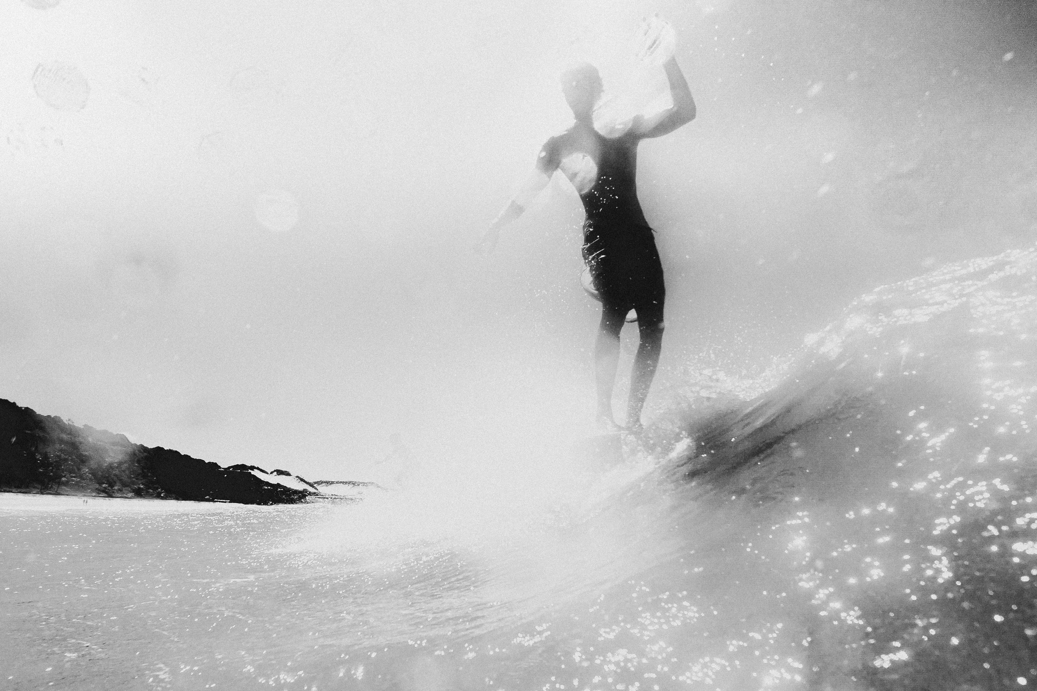 A dynamic black and white shot of a surfer riding a wave near Pipa, Brazil.