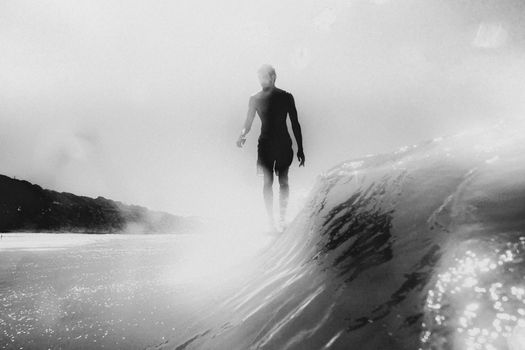 Silhouette of a surfer riding a wave in a black and white scene at Pipa Beach, Brazil.
