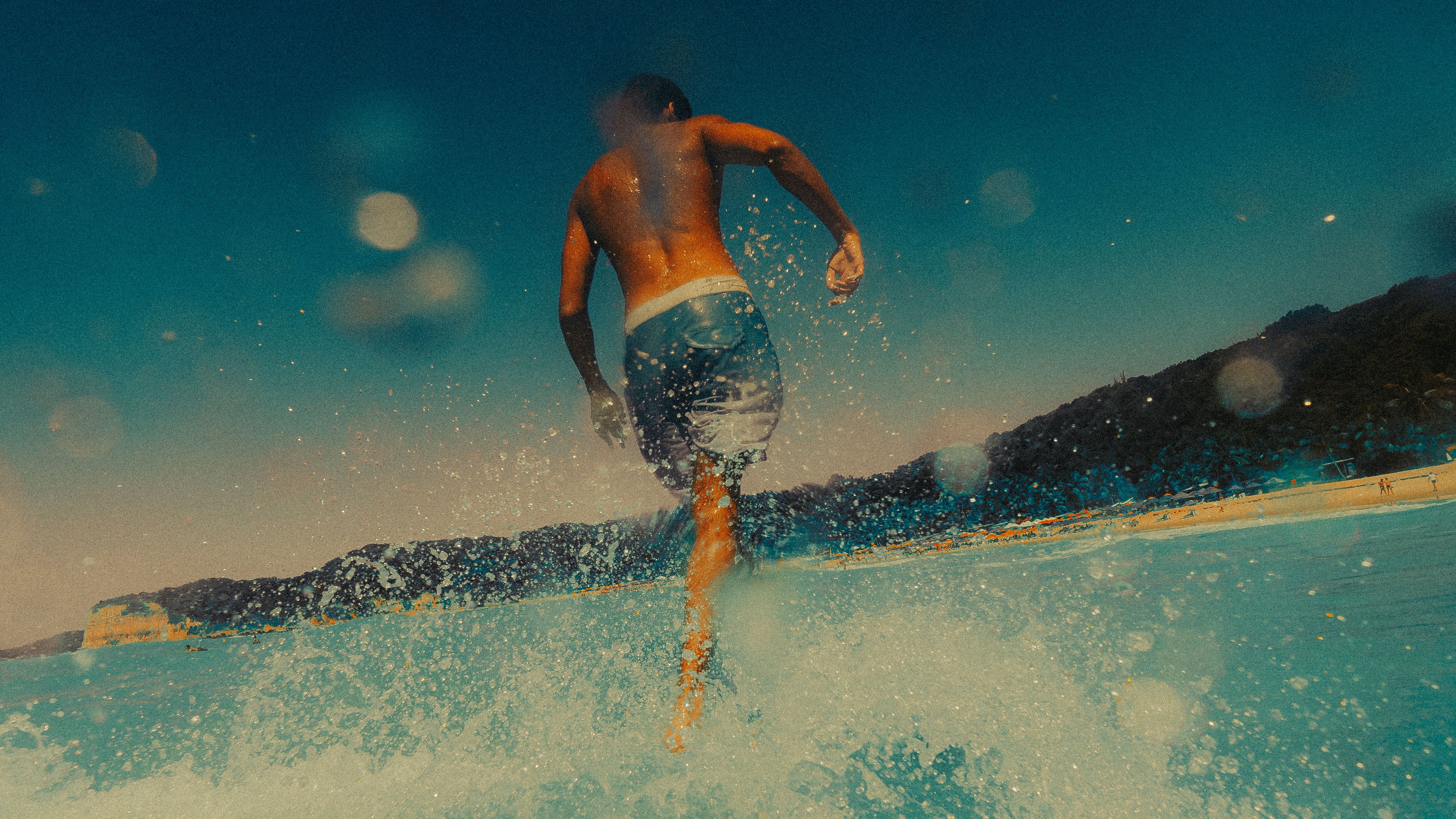 A man enjoying a summer day running through ocean waves at Pipa Beach, Brazil.