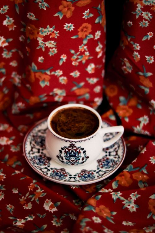 Free Stylish coffee cup with intricate design on vibrant floral fabric background. Stock Photo