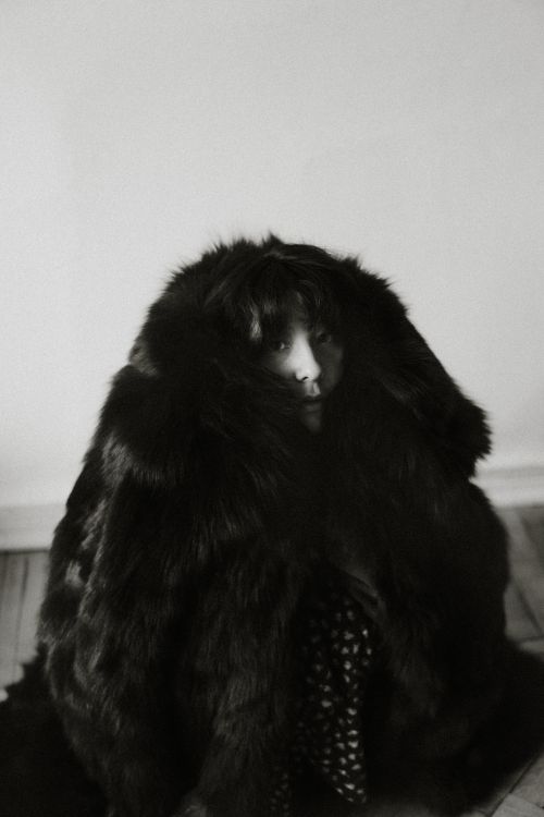 Free Black and white portrait of a woman partially hidden by a large fur coat, creating an eerie and mysterious ambiance. Stock Photo