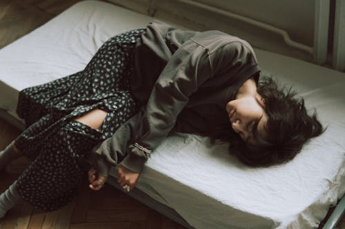 A woman sleeping on a bed with a blanket