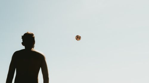 Free Silhouette of a man looking at a football in the sky, captured during a warm summer day. Stock Photo