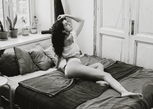 A woman in underwear sitting on a bed