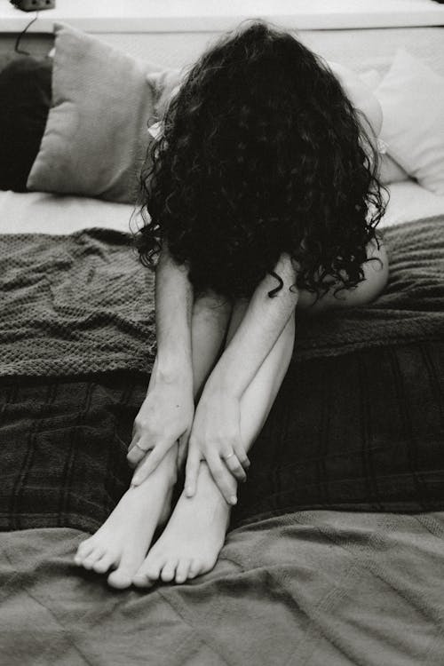 A black and white photo of a woman sitting on a bed