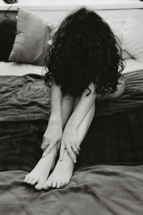 Free Black and white portrait of a woman sitting on a bed in deep contemplation. Stock Photo