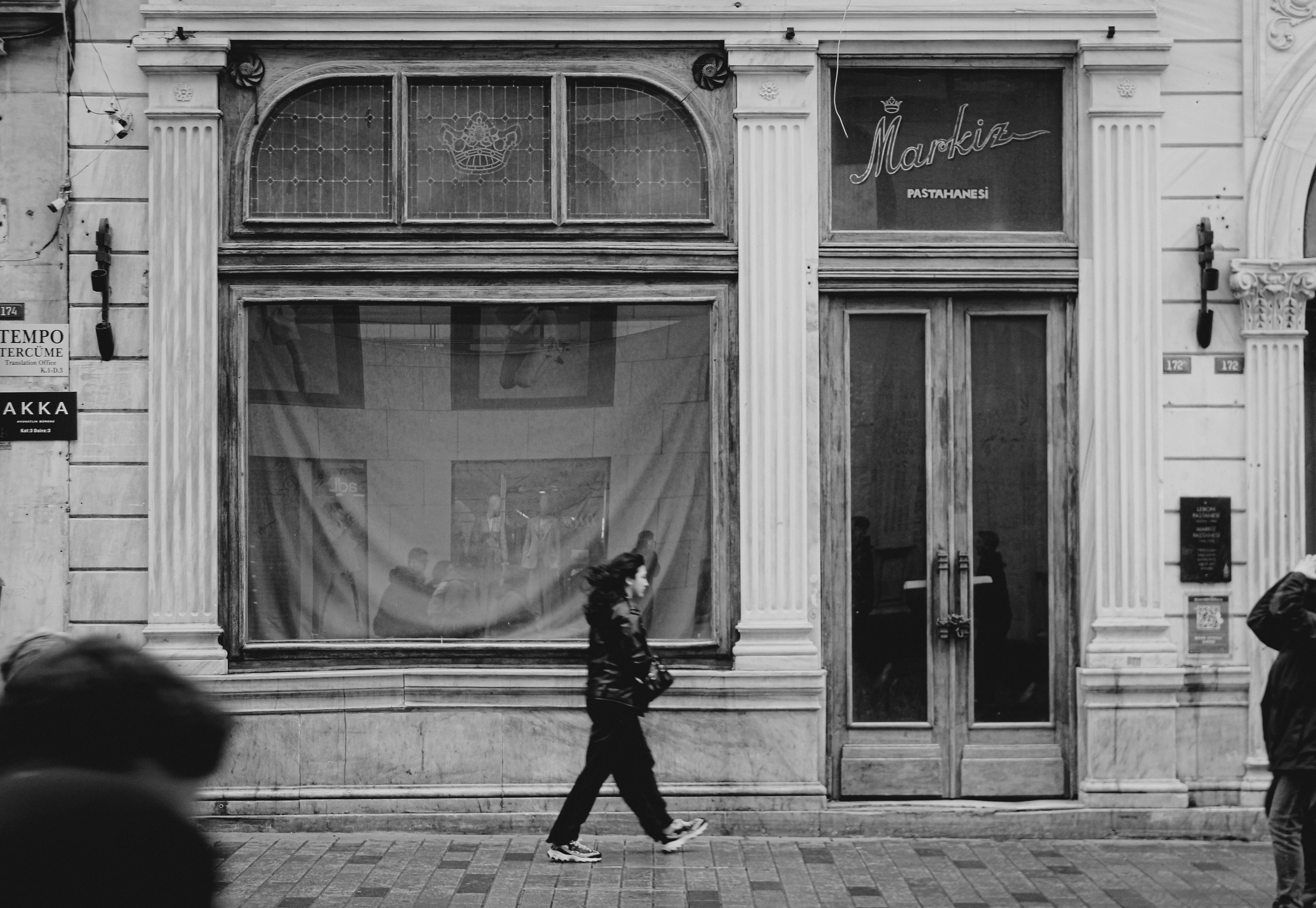 Woman in Jacket Walking on Sidewalk in Black and White · Free Stock Photo