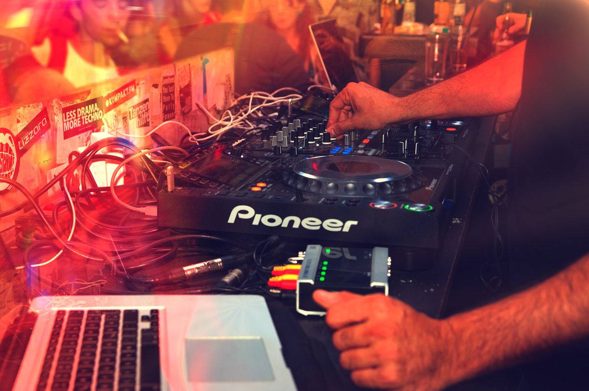 DJ mixing on a turntable under vibrant club lights, representing BTS6's range of sound