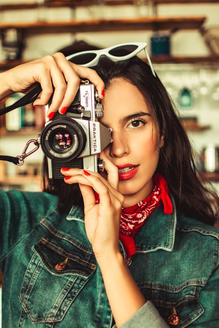 Charming young woman holding a vintage camera indoors. Stylish and vibrant.