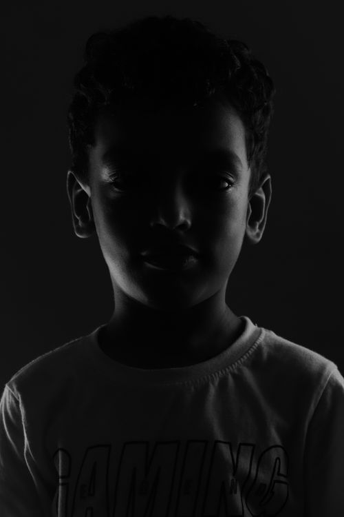 Free Striking black and white portrait of a young boy in a studio, creating a mysterious and moody atmosphere. Stock Photo