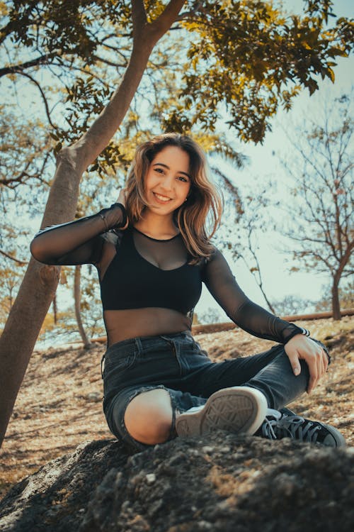 A woman in a black top sitting on a rock