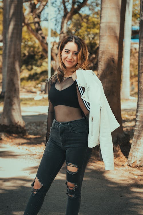 A woman in ripped jeans and a white jacket