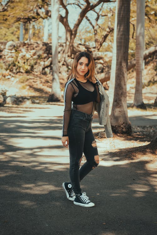 A woman in black jeans and a top standing in the park