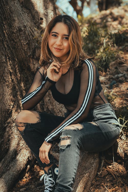 A woman sitting on a tree with her legs crossed