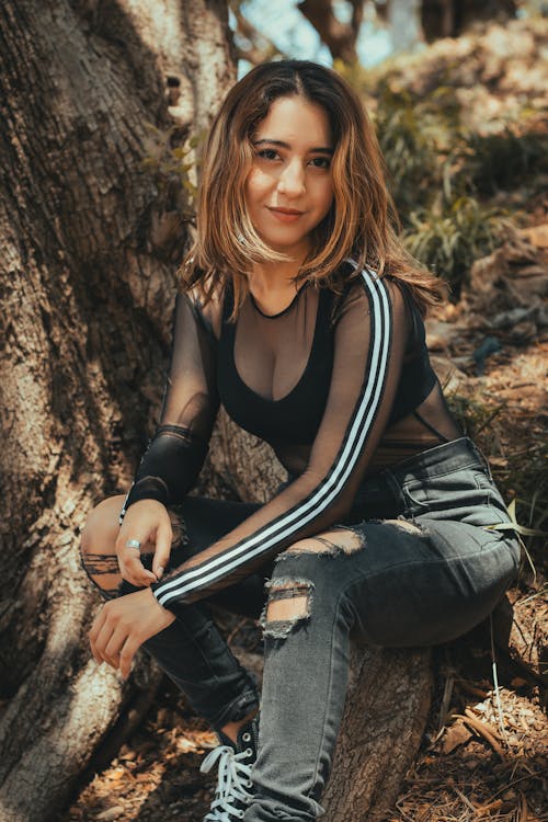 A young woman sitting on a tree trunk