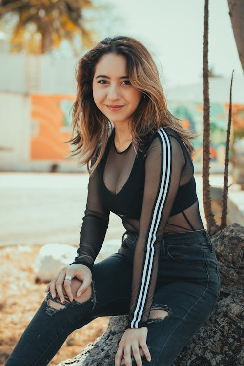 A woman in black and white top sitting on a tree