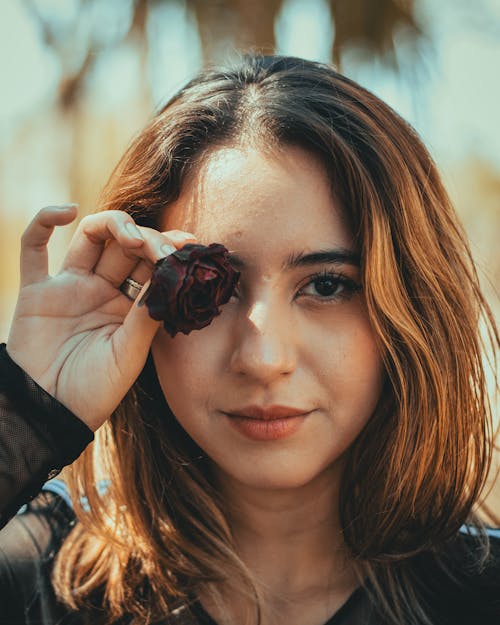 A woman holding a rose in front of her face