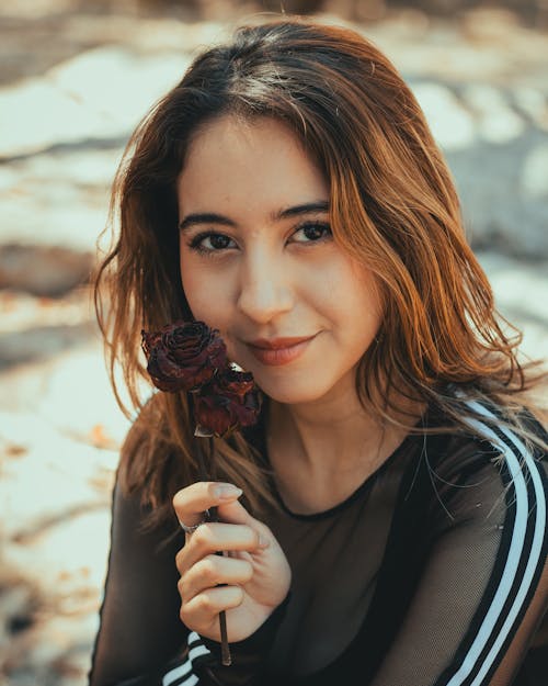 A woman holding a rose in her hand