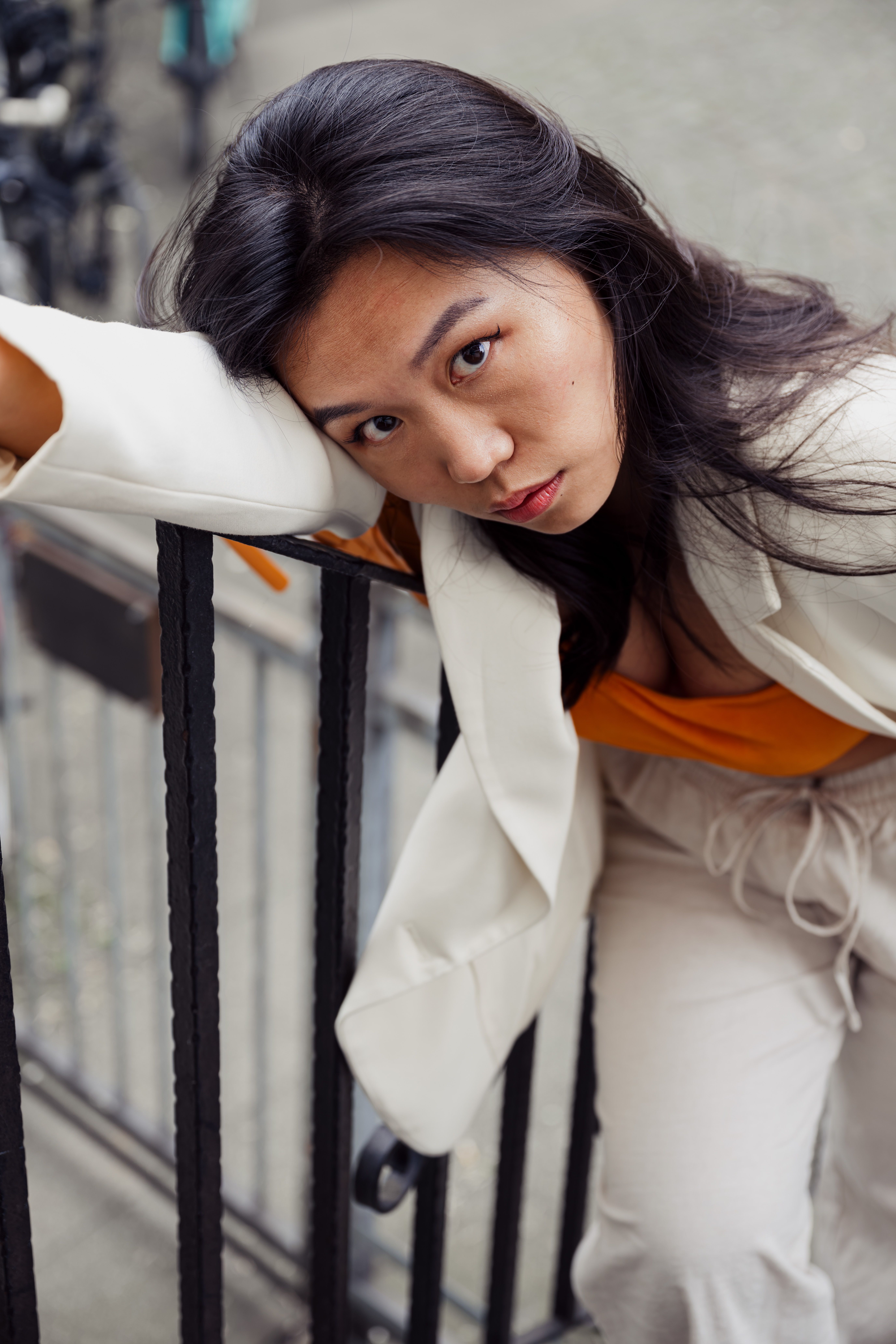 Young woman in stylish outfit leaning on railing outdoors in Cologne, Germany.