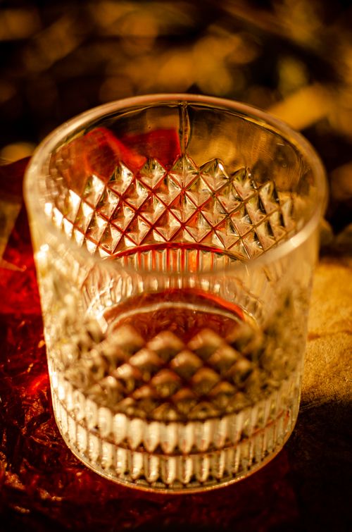 Free Artistic shot of an empty crystal glass with a decorative pattern, bathed in warm light. Stock Photo