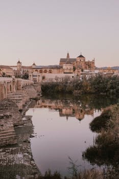 A serene landscape showcasing the Roman Bridge and historic Mosque-Cathedral of Cordoba at dusk.