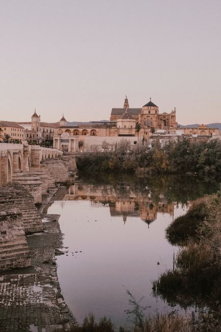 A serene landscape showcasing the Roman Bridge and historic Mosque-Cathedral of Cordoba at dusk.